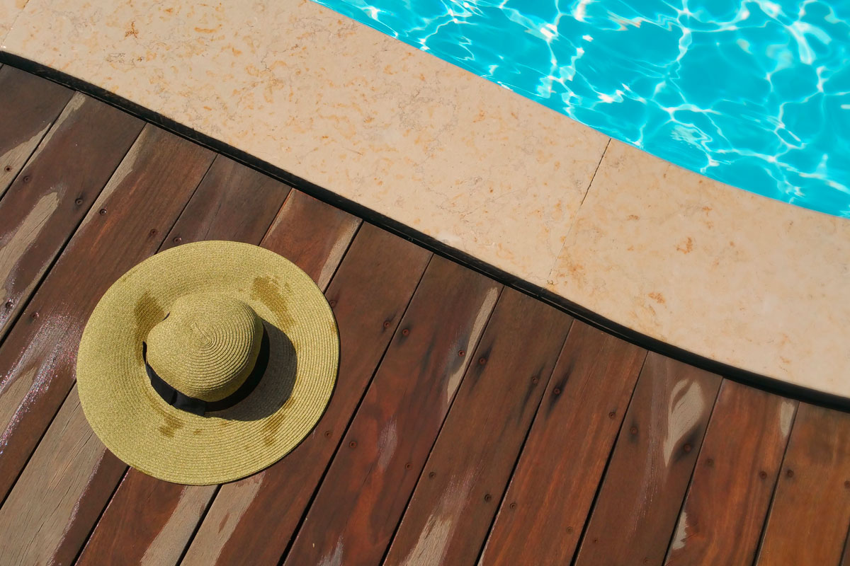 beach hat laying on a deck next to a swimming pool
